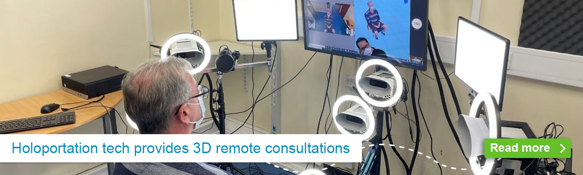 Elderly male patient sitting in front of various video cameras while viewing consultants on computer screen