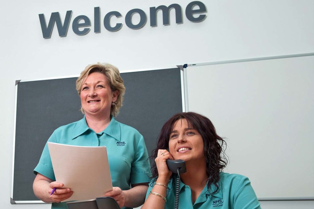 Welcome to hospital image. Two smiling, female receptionists