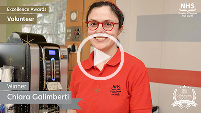 Female volunteer, in an orange uniform standing beside a coffee machine