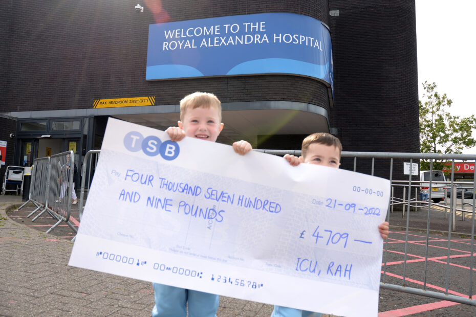 Two boys with cheque outside hospital