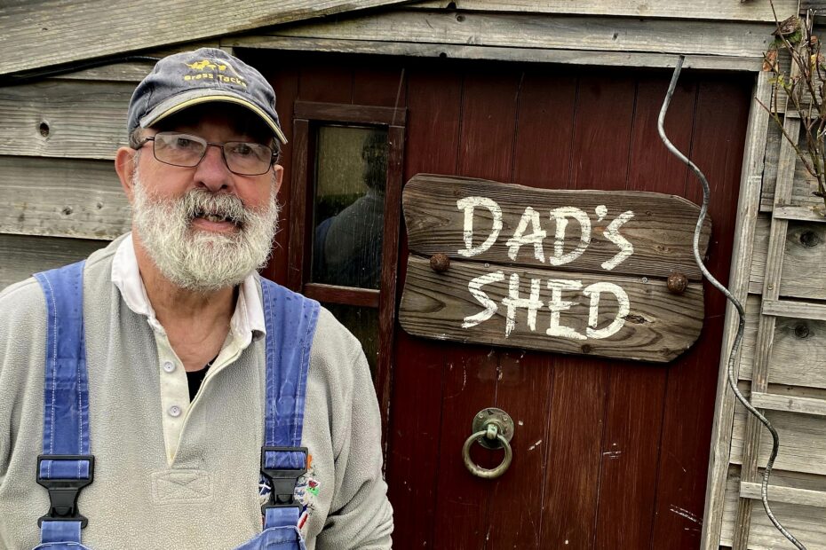 Campbell McDonald beside door to his workshop, with sign saying 'Dad's Shed' on the door.