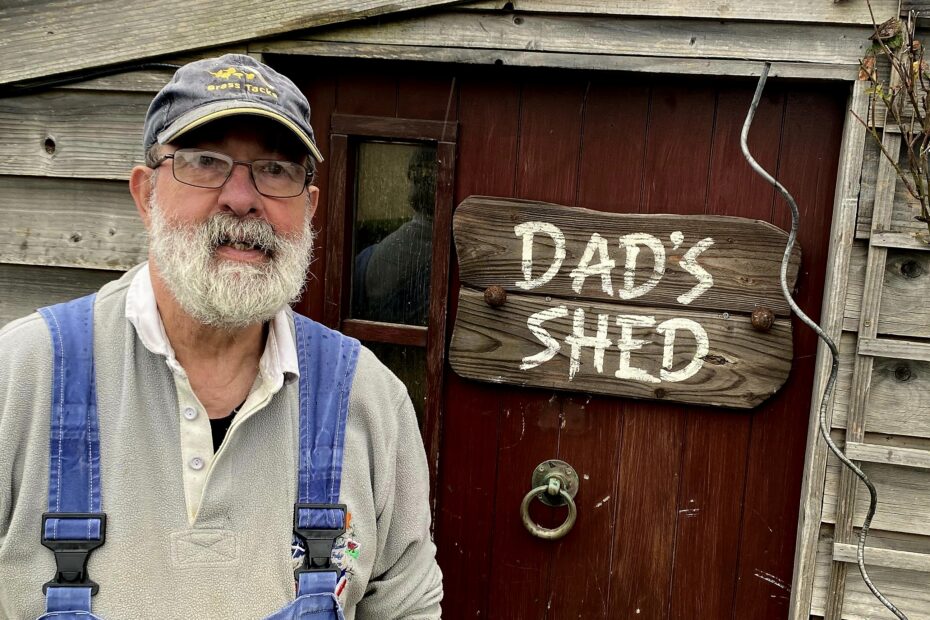 Campbell McDonald beside door to his workshop, with sign saying 'Dad's Shed' on the door.