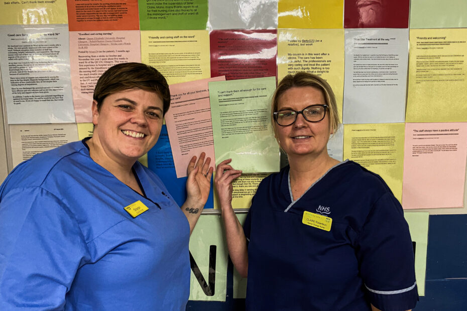 Two smiling nurses stand beside a board displaying dozens of messages of thanks from former patients and relatives.