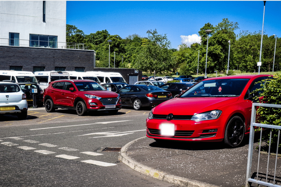 Cars parked outside the New Victoria Hospital, with one red car parked on a pavement.