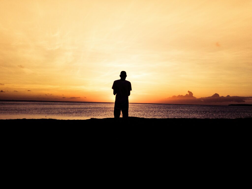 Man in silhouette against a sunset above the sea