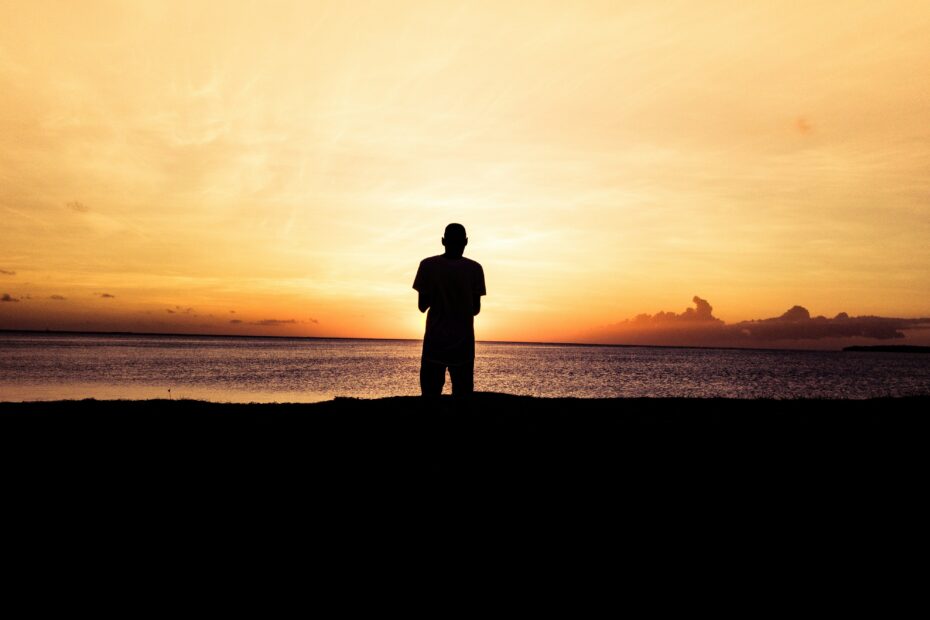 Man in silhouette against a sunset above the sea