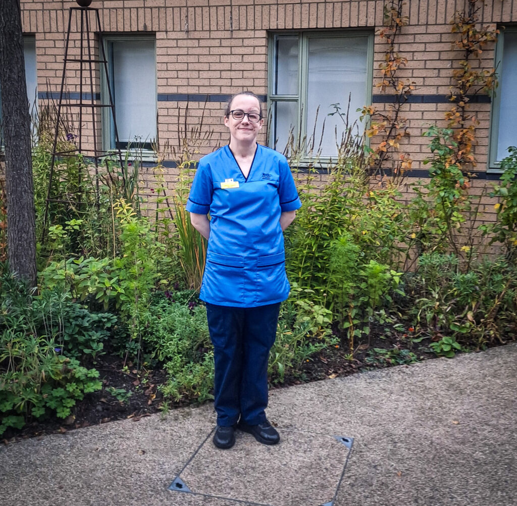 Ashley Sneddon stands in front of plants in the garden at the National Spinal Injuries Unit.