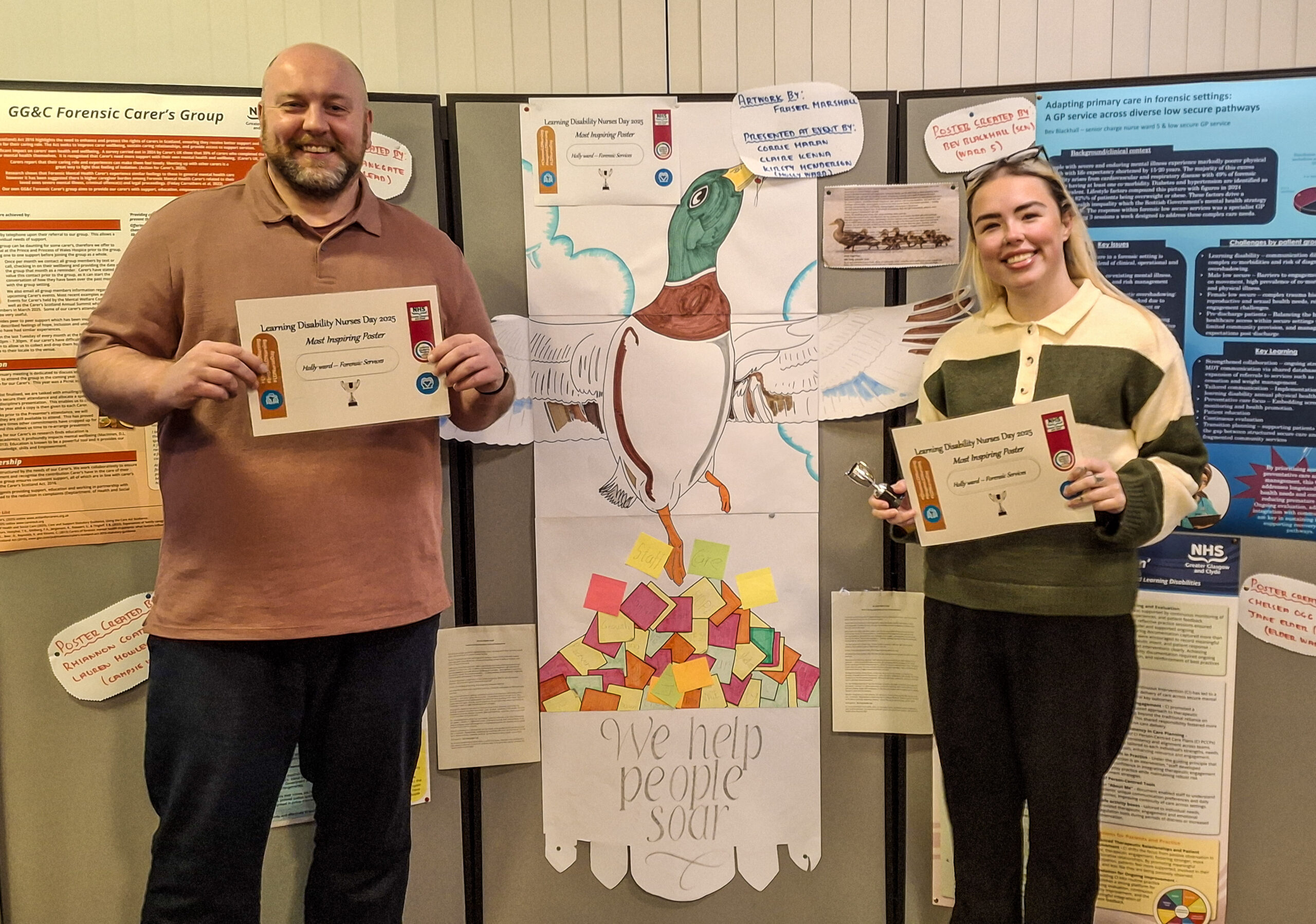Staff member Fraser Marshall and student nurse Kirsty Henderson stand either side of the poster, holding certificates for their successful presentation.