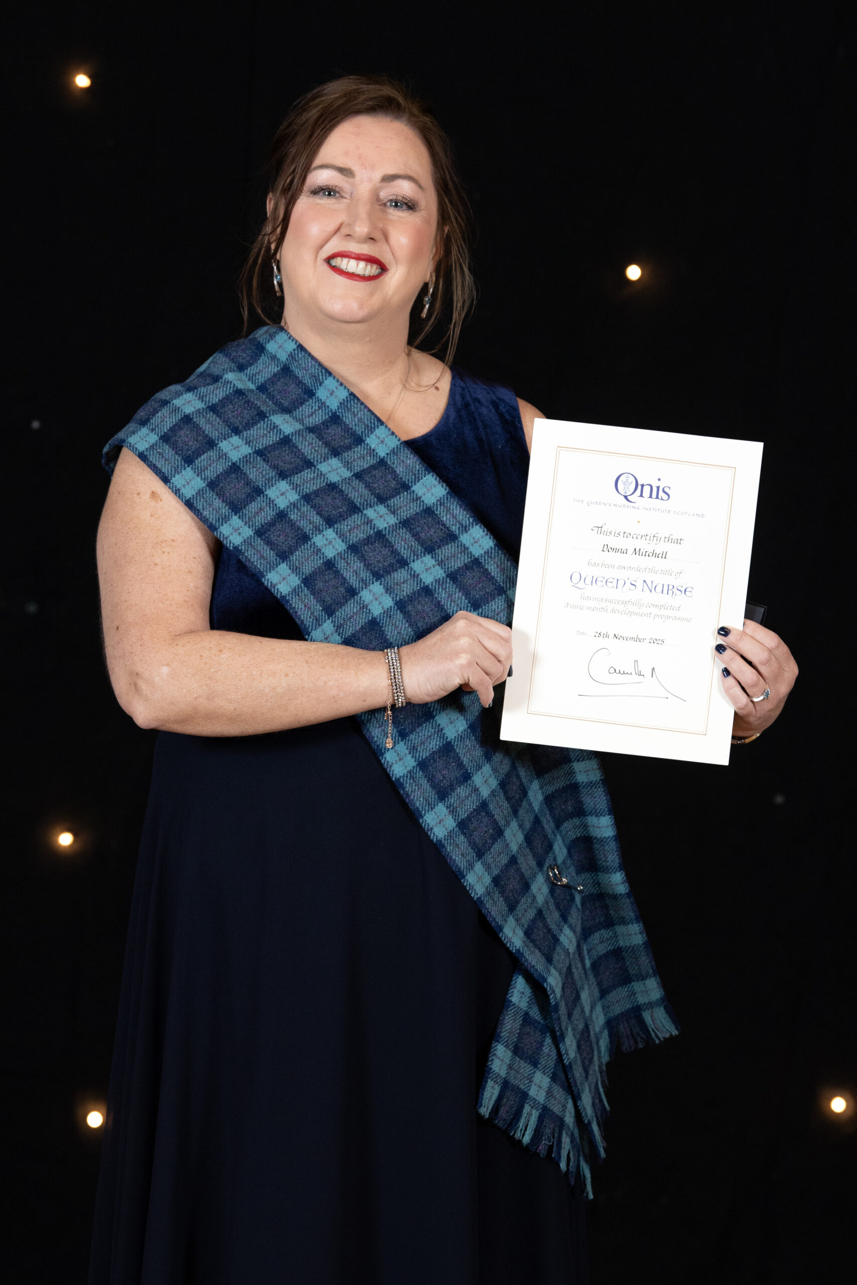 Donna Mitchell smiling as she holds her Queen's Nurse award.
