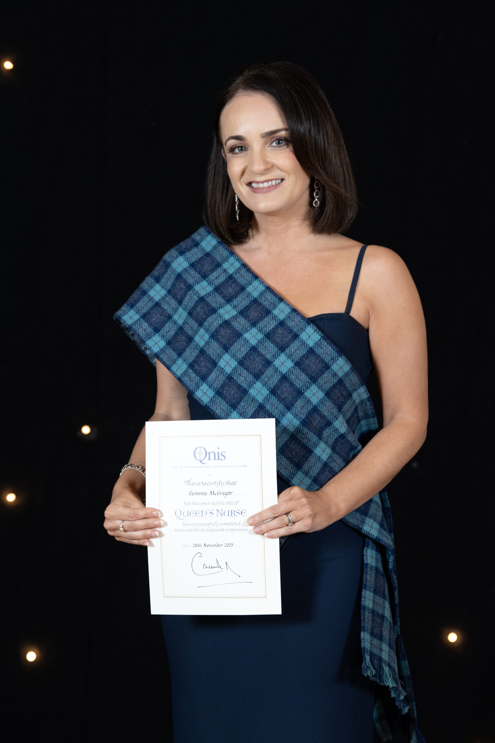 Gemma McGregor smiling as she holds her Queen's Nurse award.