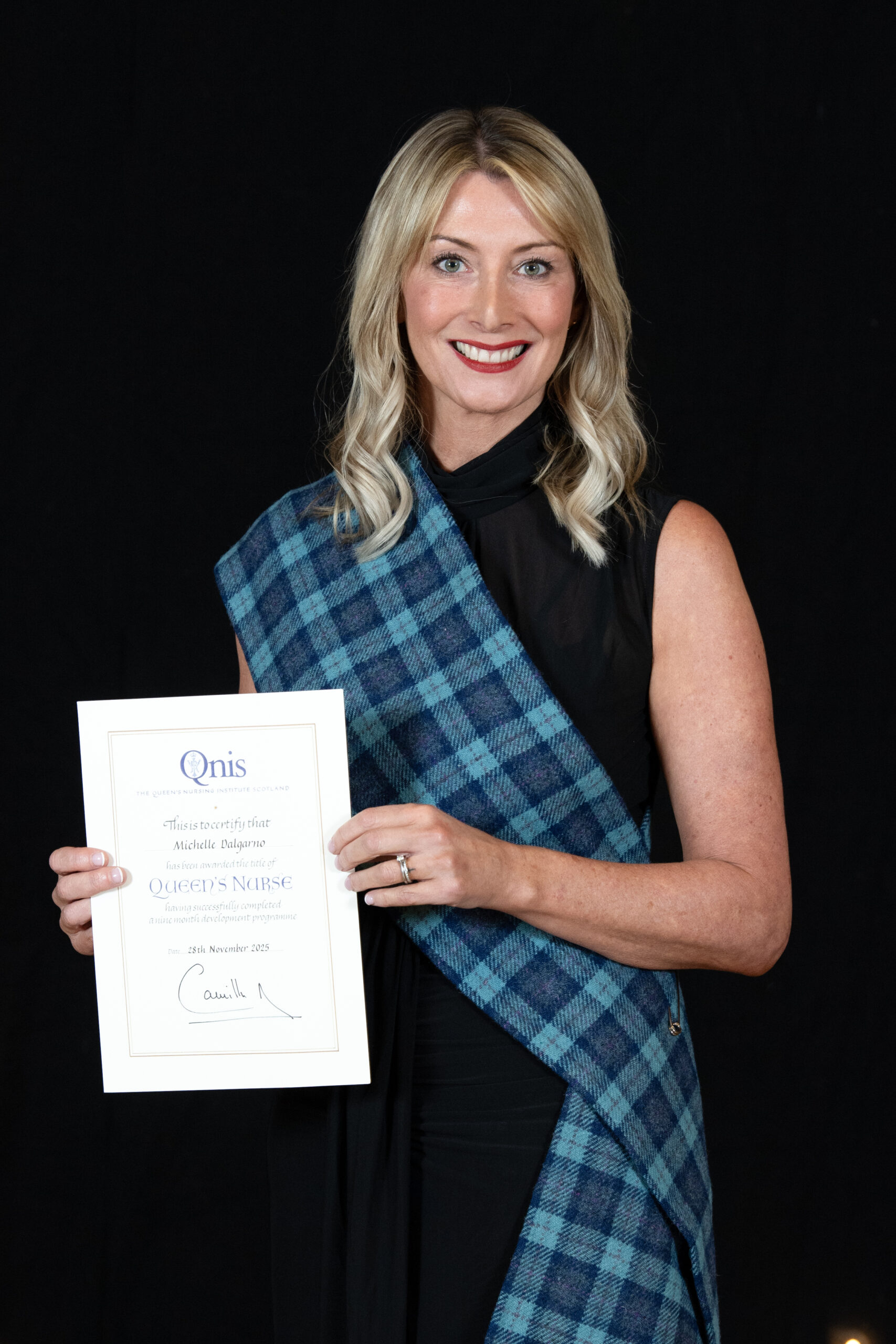Michelle Dalgarno smiling as she holds her Queen's Nurse award.