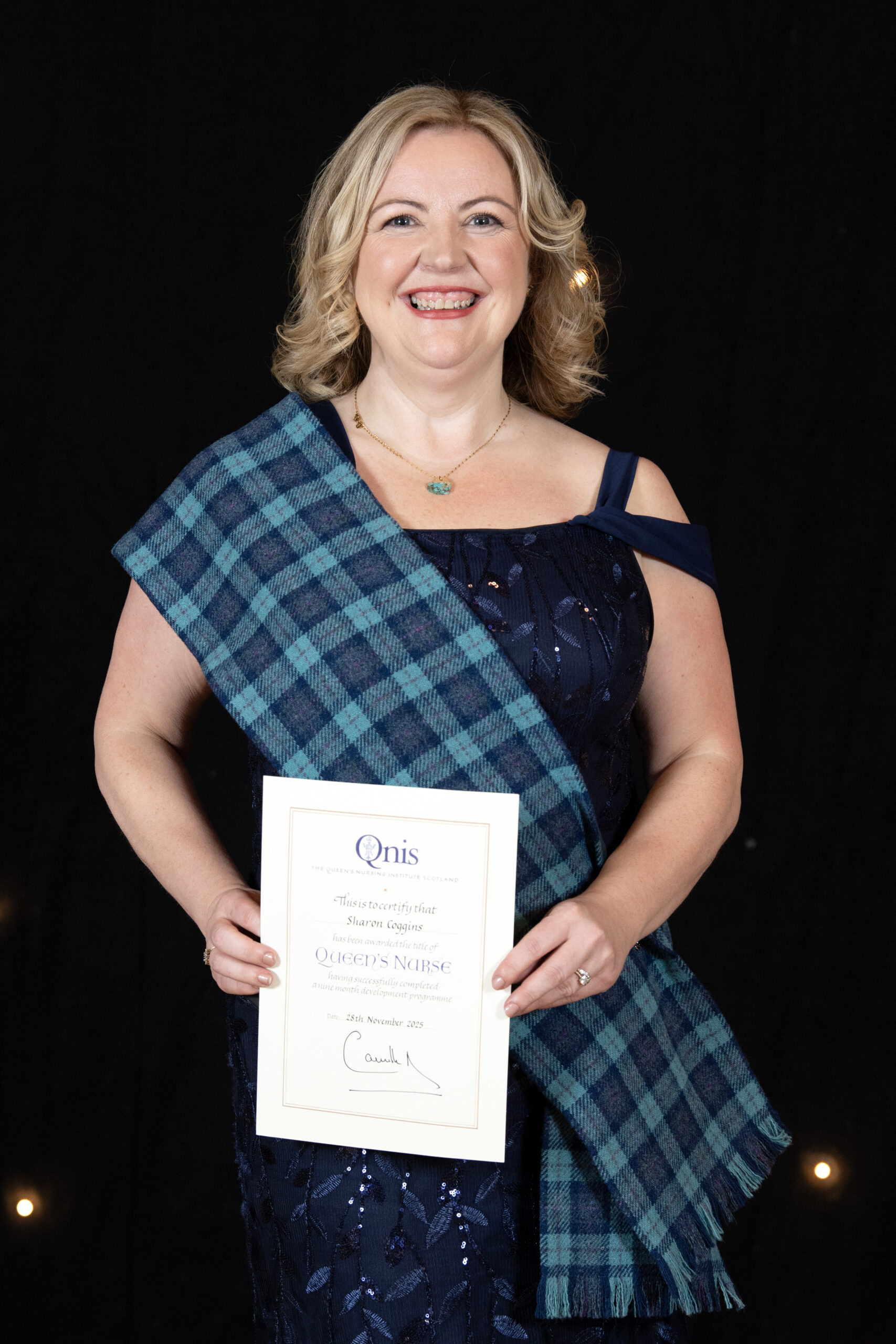 Sharon Coggins smiling as she holds her Queen's Nurse award.