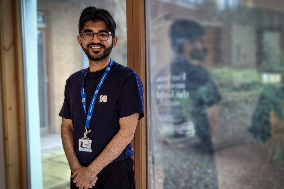 Raiyan Mehmood smiles as he stands next to a large window at the Centre for Integrated Care. The centre's garden can be seen outside.