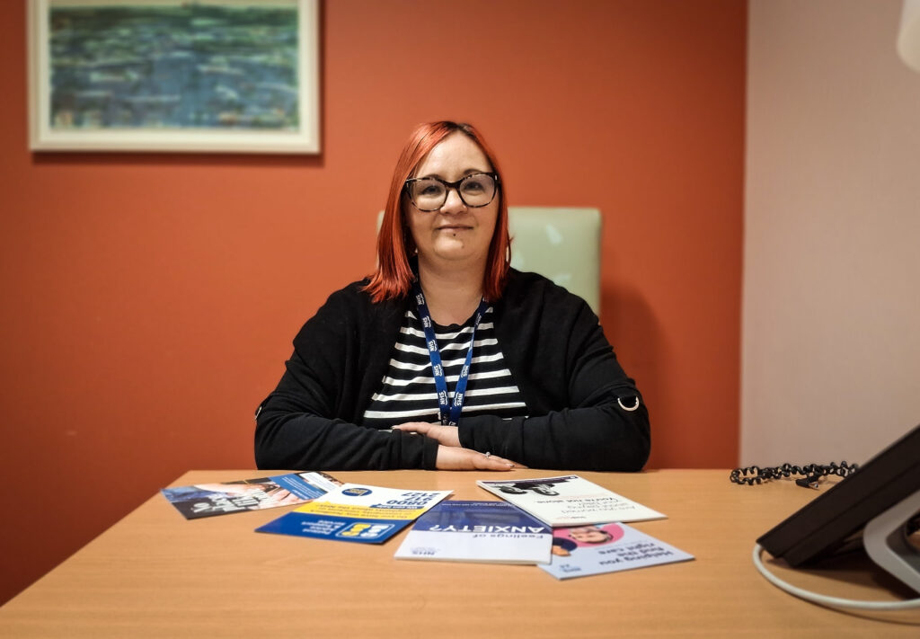 Money Adviser Lisa-Marie McErlane sits at a desk with leaflets and advise booklets in front of her.