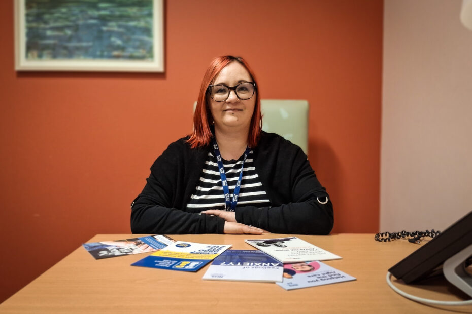 Money Adviser Lisa-Marie McErlane sits at a desk with leaflets and advise booklets in front of her.