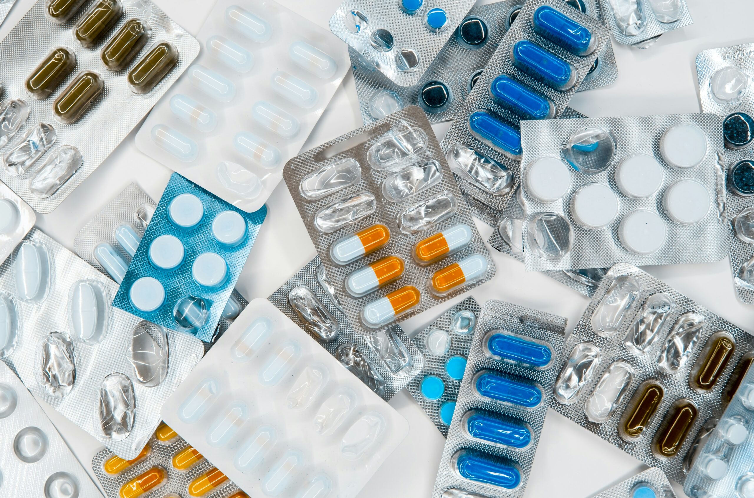 A range of pills and tablets in their packaging spread out in a random pile