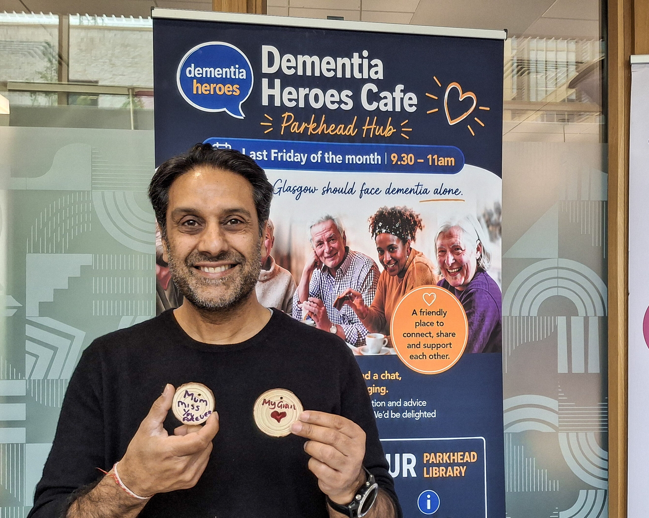 Arvind Salwan, founder of Dementia Heroes, holding who discs of wood with writing on.