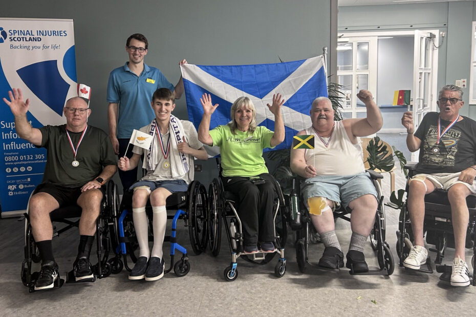 A line-up of patients and volunteers, with a Saltire in the background and each patient holding a flag from the competing countries