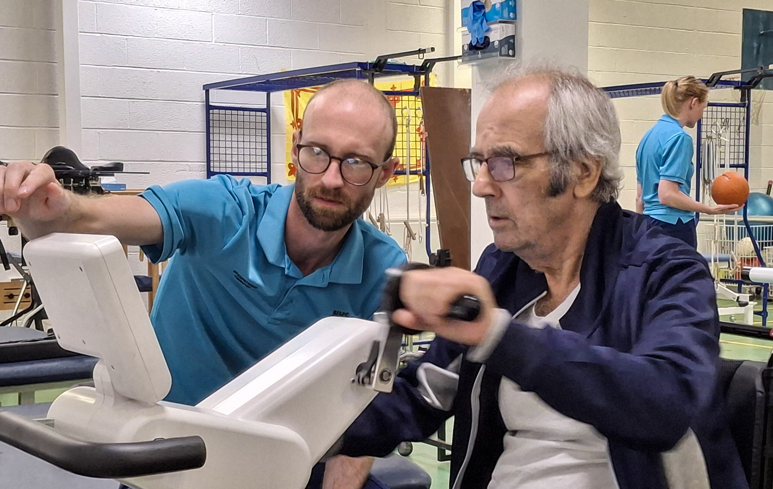 A patient competes in hand-cycling, supported by a staff member