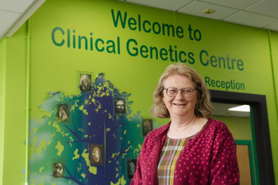 Professor Zosia Miedzybrodzka, Service Clinical Director of Genetics at NHS Grampian, standing outside the Clinical Genetics Centre. The name of the centre of printed in large dark green letters on a light green background