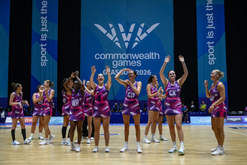 Members of the Scotland netball team, stand waving and smiling on court following a match at the Commonwealth Games