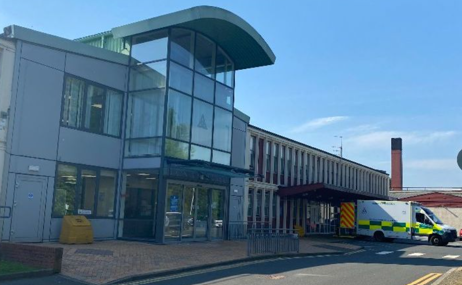 External image of the Vale of Leven Hospital entrance, with an ambulance parked at the right and a blue sky