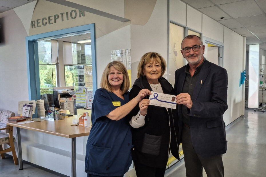 Ethel Smith (centre) holds a queue for £50,000 with Charge Nurse June Raines in uniform on the left and Gerry O'Hare on the right. The picture is taken in front of reception at the Vale of Leven oncology unit.