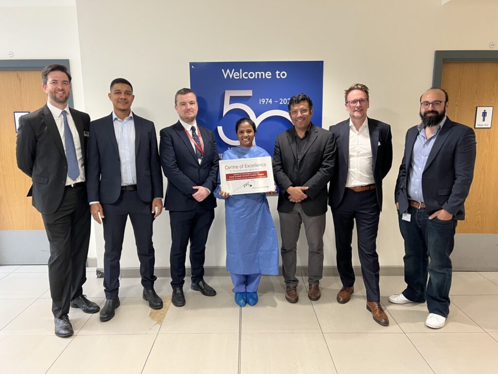 Members of the INS team gather in the atrium of the INS with the Centre of Excellence award.