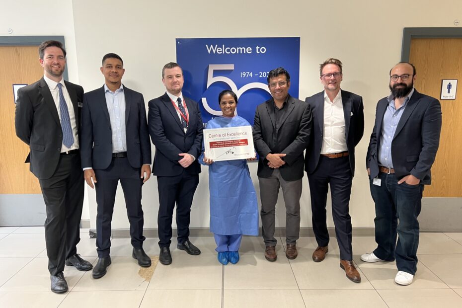 Members of the INS team gather in the atrium of the INS with the Centre of Excellence award.