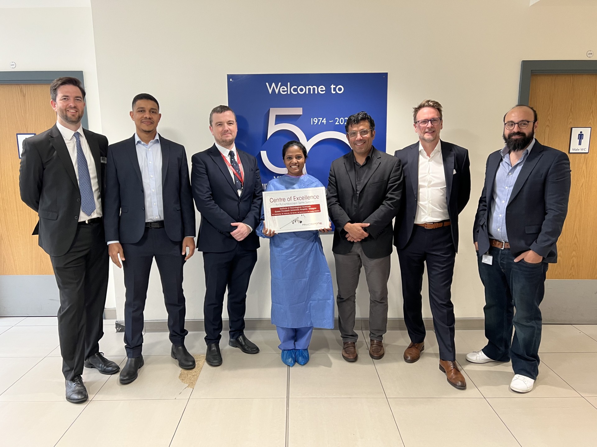 Members of the INS team gather in the atrium of the INS with the Centre of Excellence award.