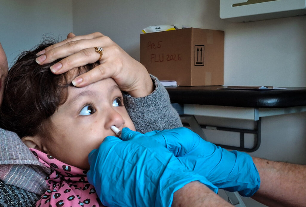 A young girl received the flu vaccine through a nasal spray at a clinic in Glasgow