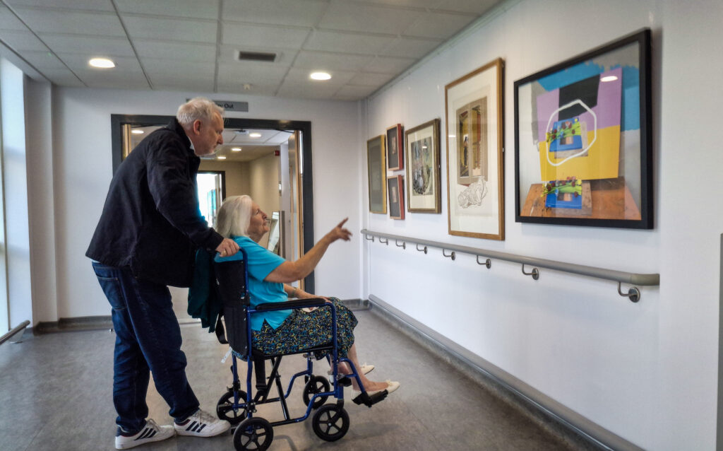 A patient in a wheelchair and a relative admire some of the works at the New Victoria Hospital.